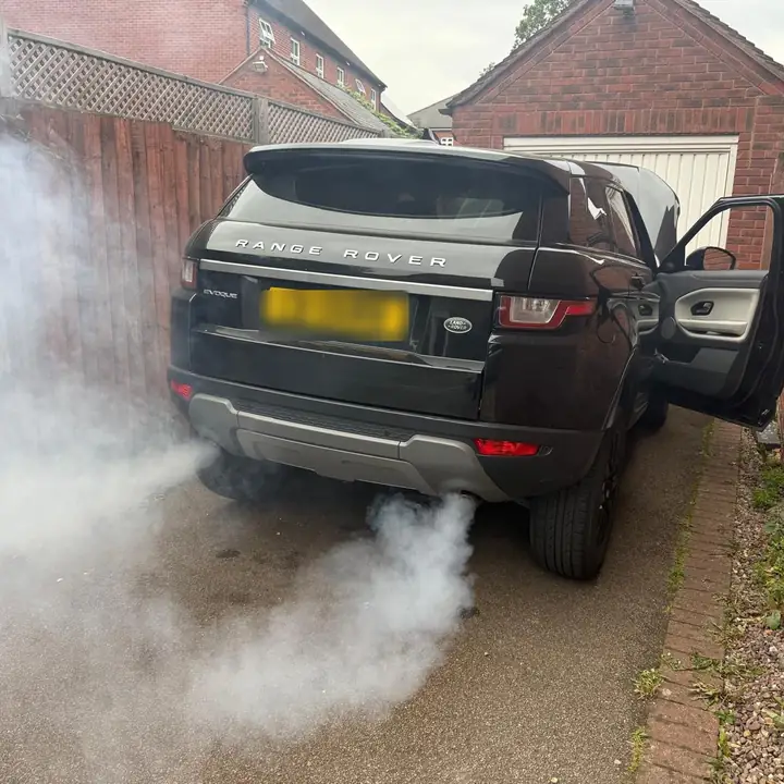 Black Range Rover Evoque on a driveway with white smoke from the exhaust during a DPF clean