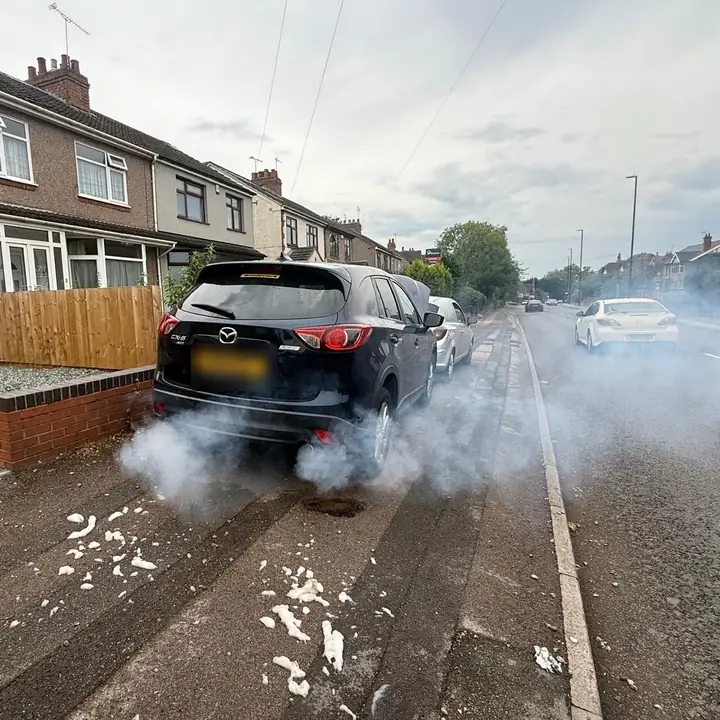 Black Mazda CX-5 parked on a residential street with smoke from the exhaust during a DPF clean